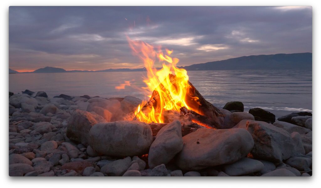 Ein brennendes Lagerfeuer an einem Seeufer