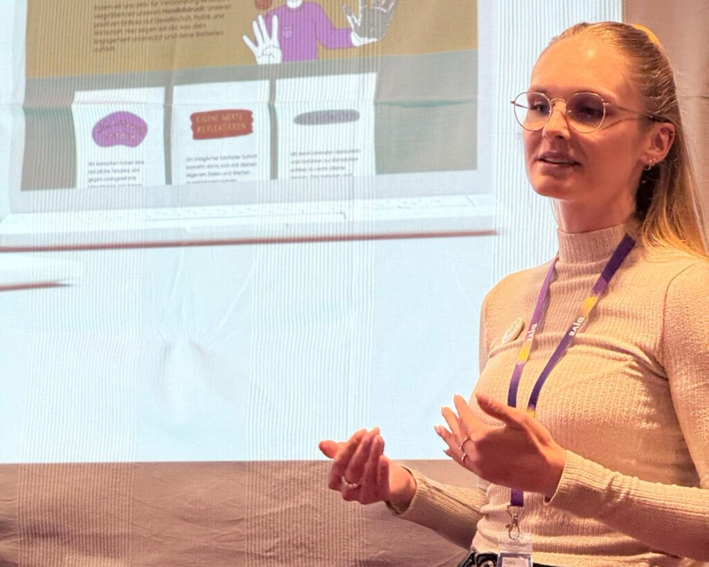 Daniela Gaulrapp spricht vor einer Leinwand mit dem Screenshot einer Website